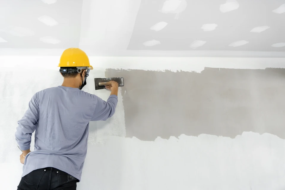 Un architecte ou ingénieur en chemise à carreaux rouge travaille sur des plans techniques dans son bureau